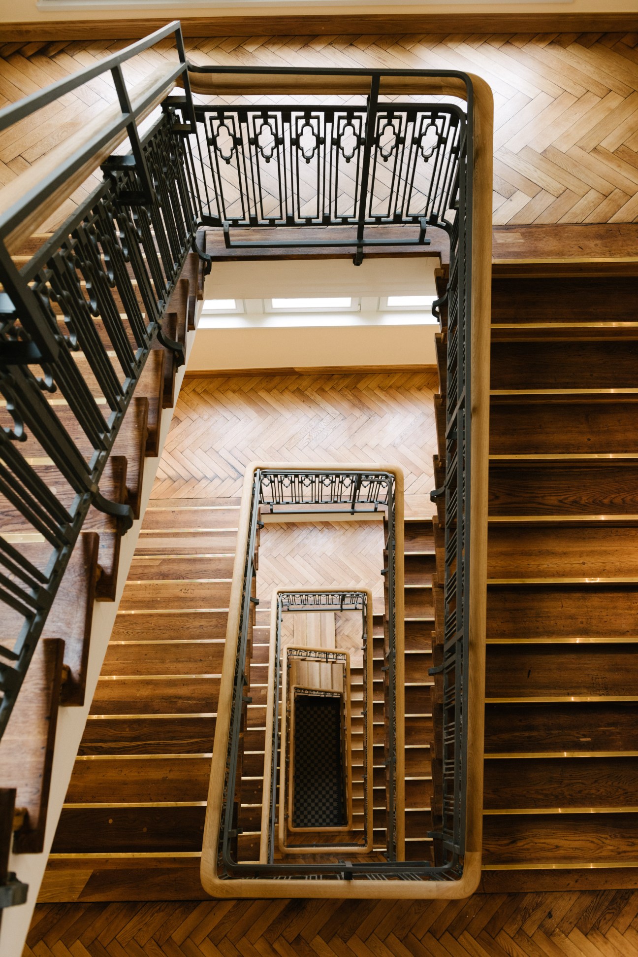 Overhead view of a beautifully renovated staircase with wooden steps and black metal railings at Orania Berlin.