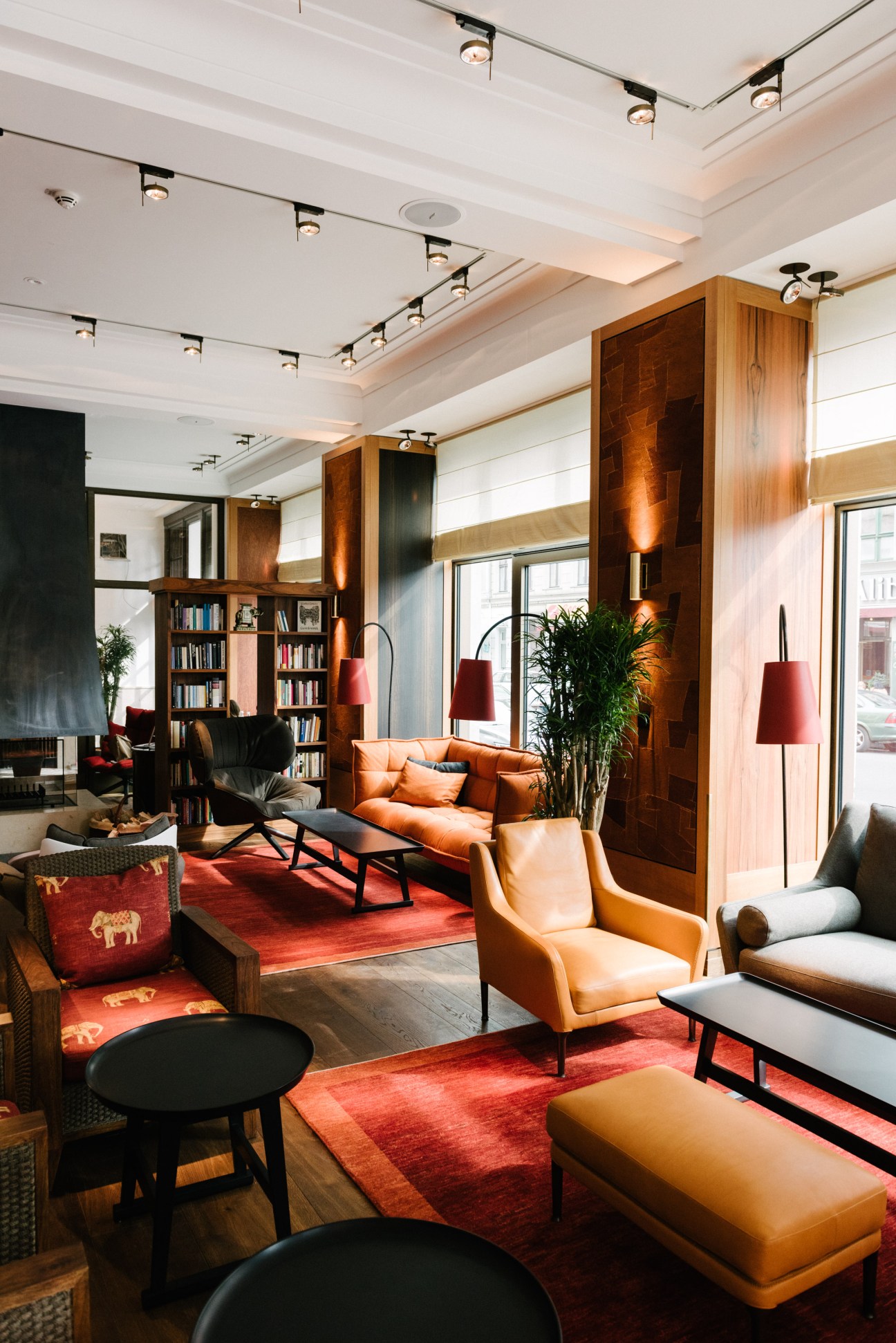 Ground floor lounge at Orania Berlin with orange leather seating, wooden pillars, red carpets and bookshelves.