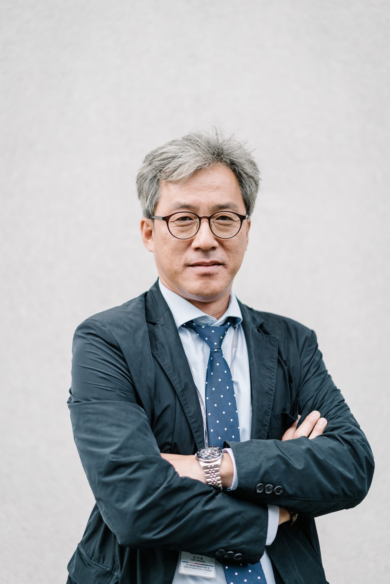 Portrait of Lee Seok-yong, head of the photo operation team for the 2018 Winter Olympics, wearing glasses and a dark blazer.