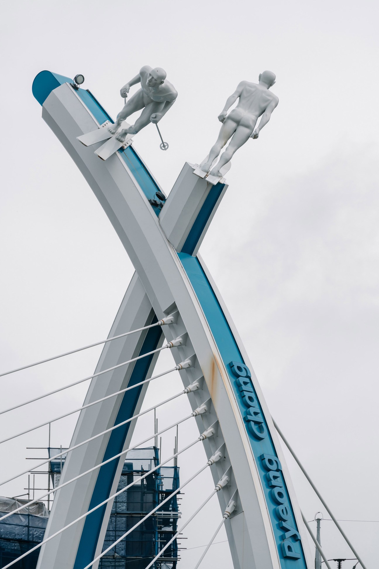 Skier statue in Hoenggye displaying two gray figures on a blue and white ski slope structure.