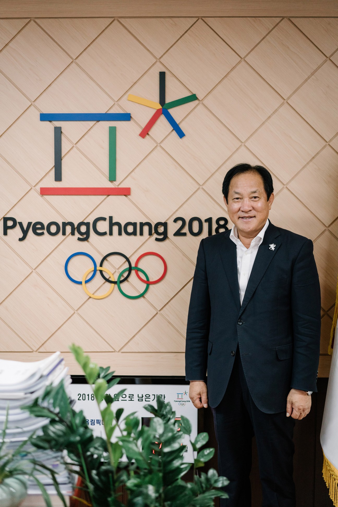 Sim Jae-kook, Pyeongchang county mayor, standing in front of PyeongChang 2018 Olympic signage and logo