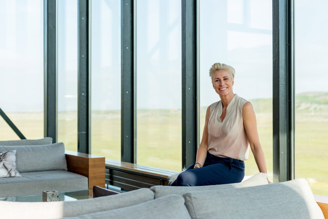 Sigurlaug Sverrisdóttir sitting on a windowsill in a modern interior with floor-to-ceiling windows