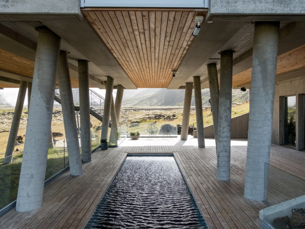 Modern concrete building with wooden ceiling and thermal pool overlooking Icelandic landscape