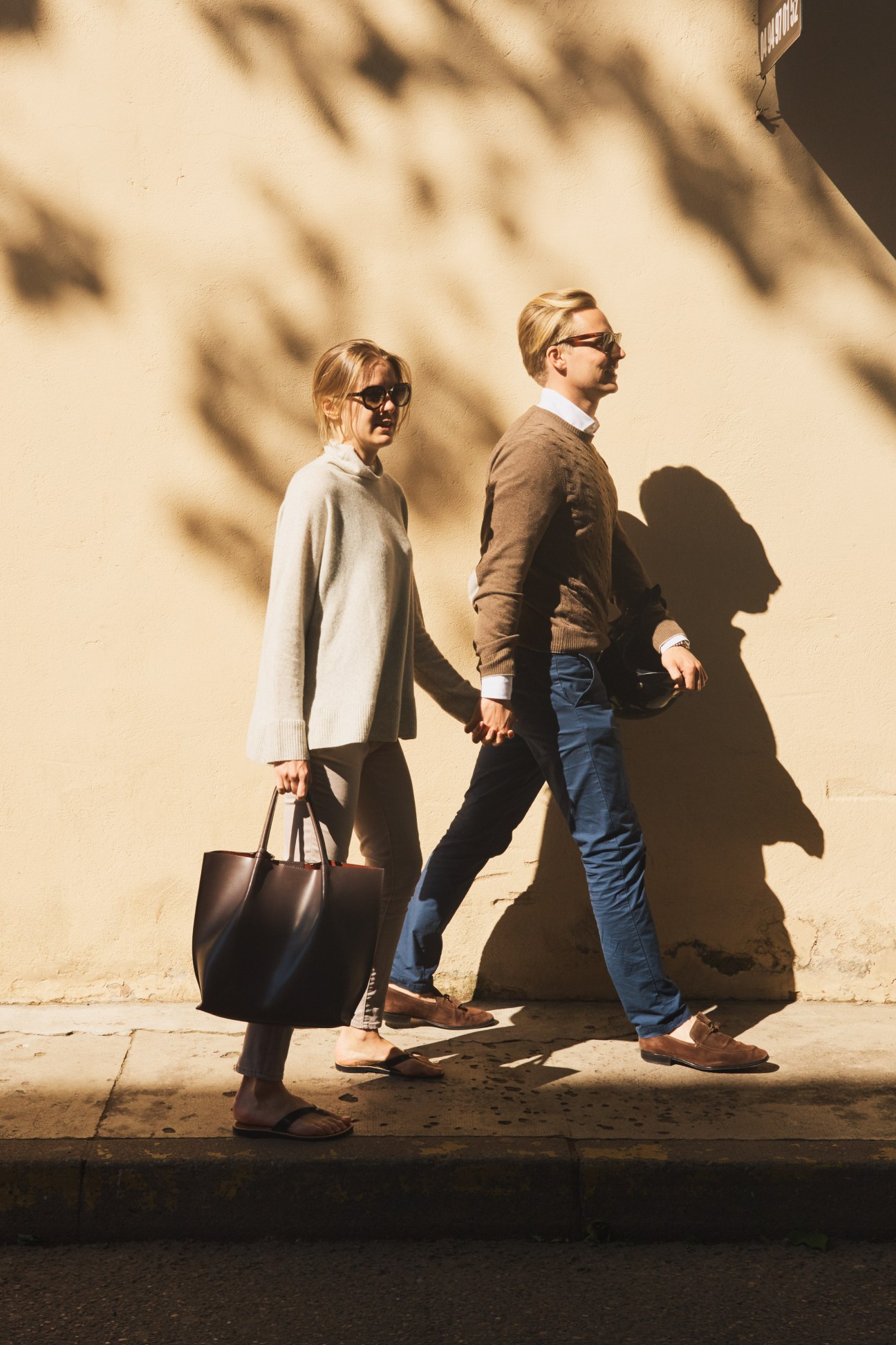 Young Swiss couple walking while shopping in St Tropez, woman carrying a black tote bag.