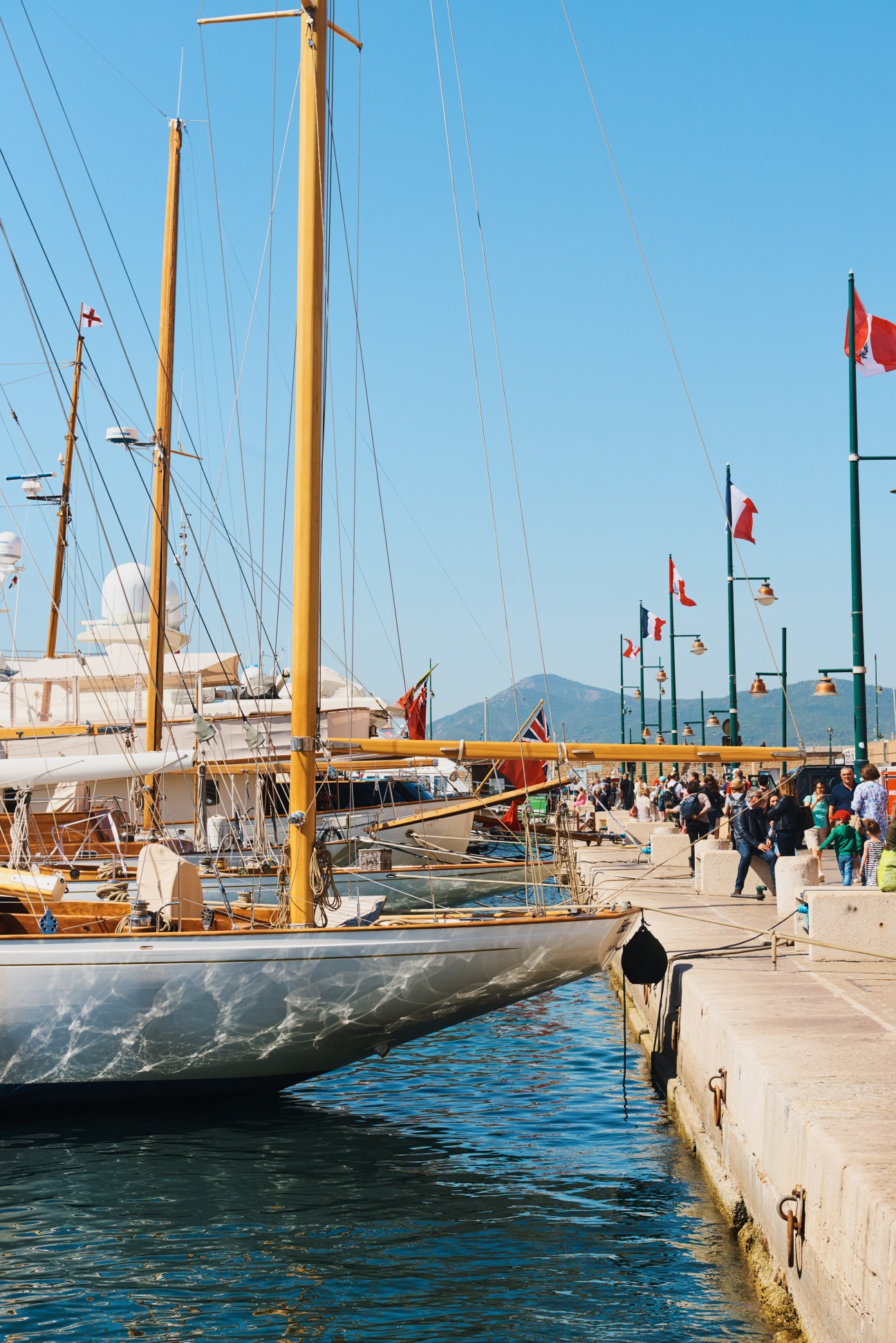 St Tropez harbour with sailing yachts moored at the dock under clear blue sky.