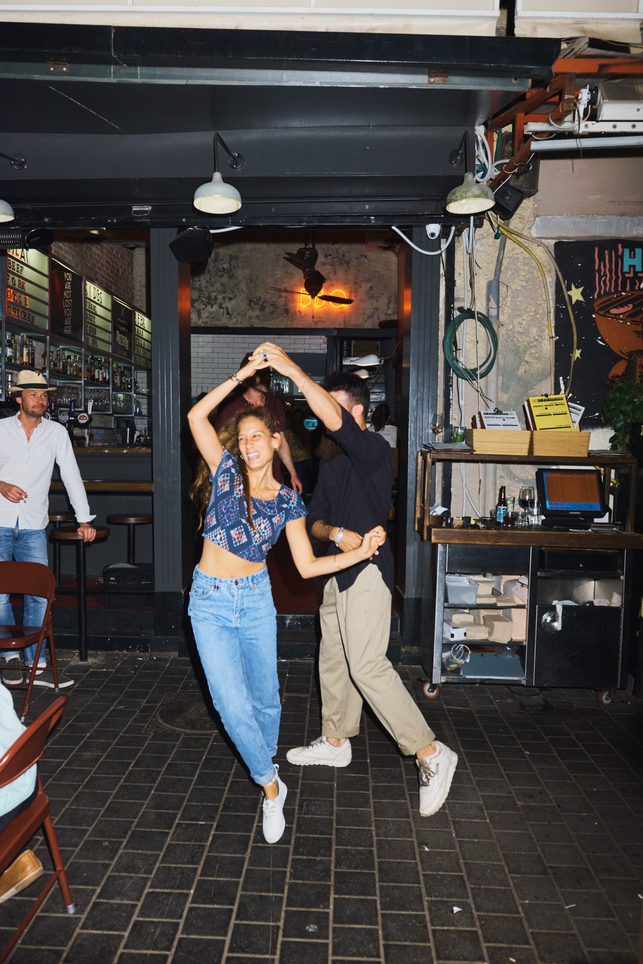 A couple dancing at Pundak Deluxe bar with staff members watching in the background.