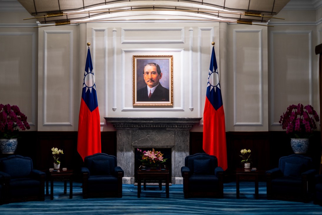 Portrait of Dr Sun Yat-sen hanging above a fireplace flanked by two Taiwan flags in an official government room.
