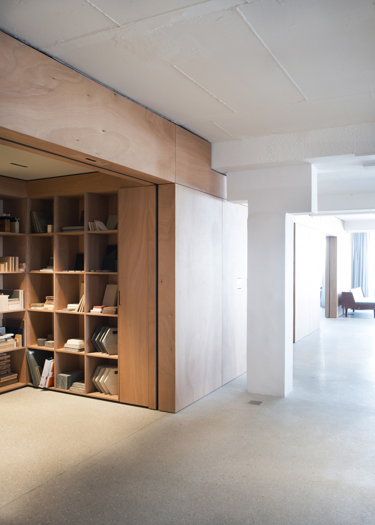 Wooden cupboards with grid-pattern doors and shelving in a modern office space with white walls and ceiling.
