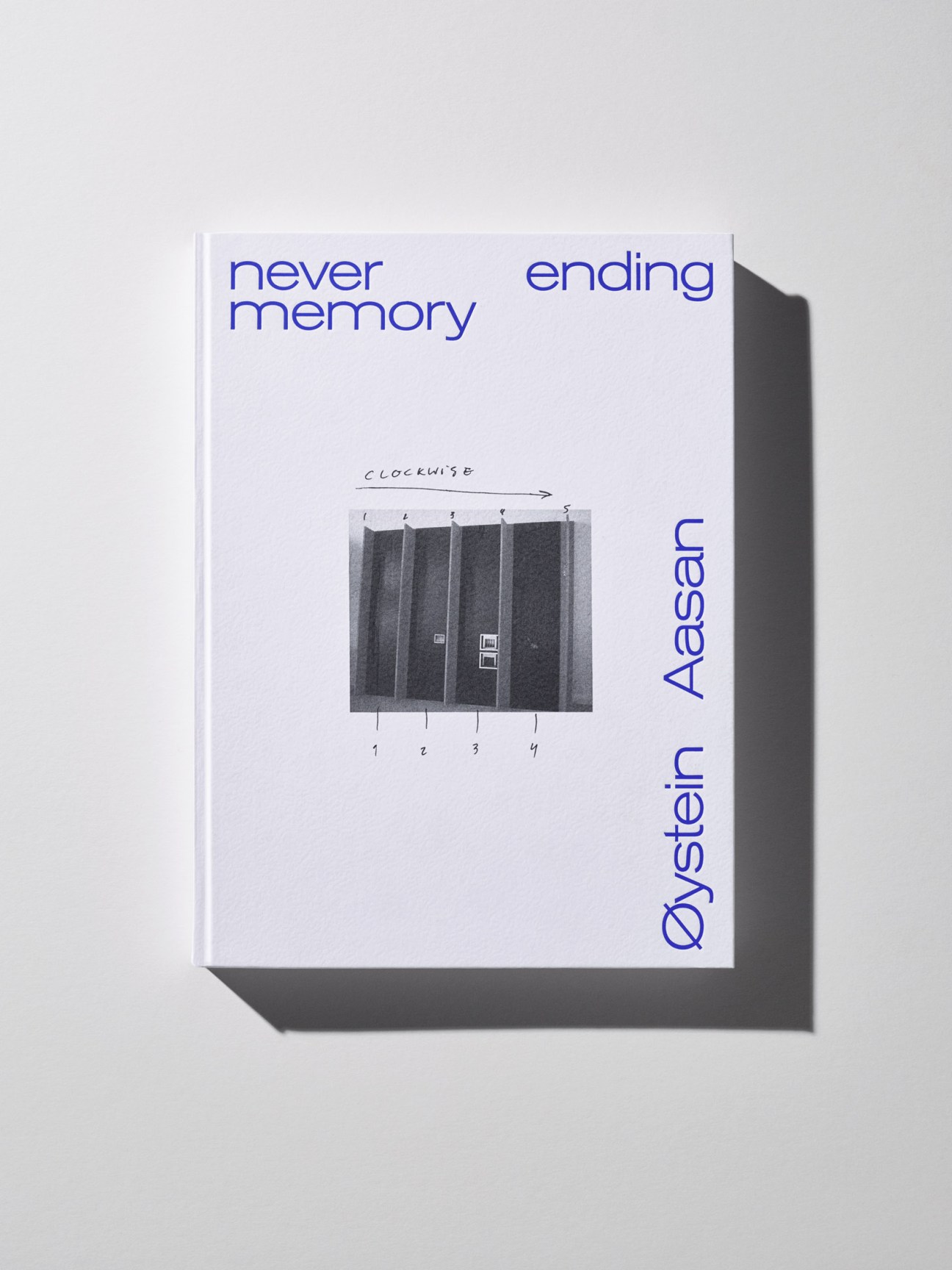 Minimalist book cover with blue text reading 'never memory ending' and 'Öystäin Aasäm', featuring a numbered black and white architectural photograph.