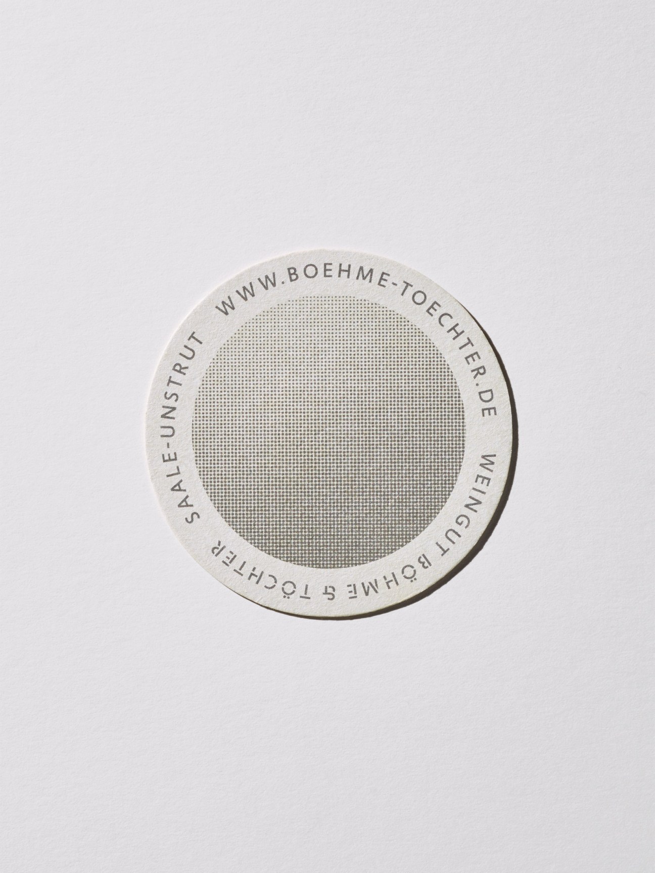 Circular paper coaster with printed text and mesh pattern design by Grabowski Böll.