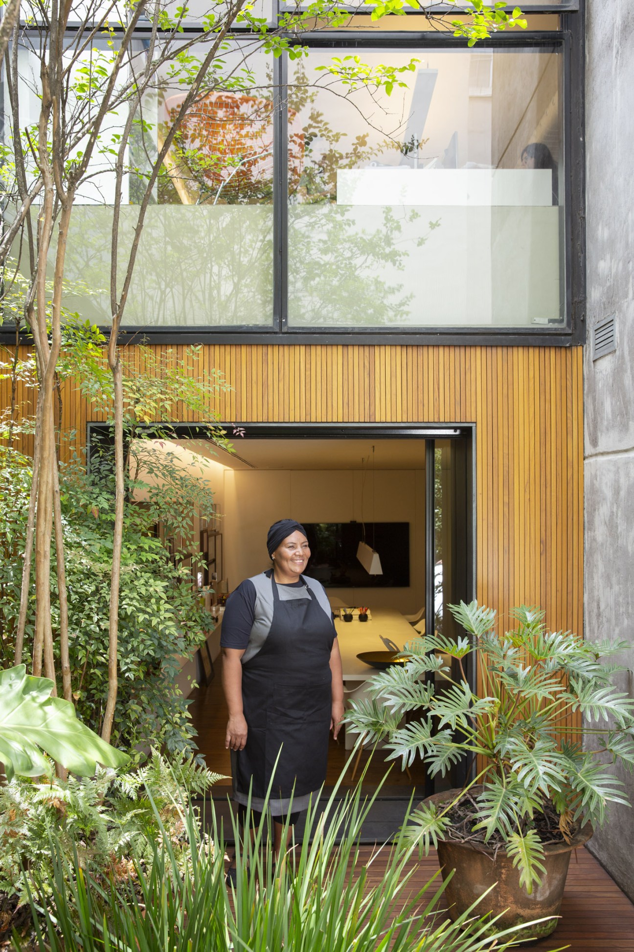 Lia da Silva, Studio mk27's in-house chef, standing in the kitchen doorway surrounded by lush plants