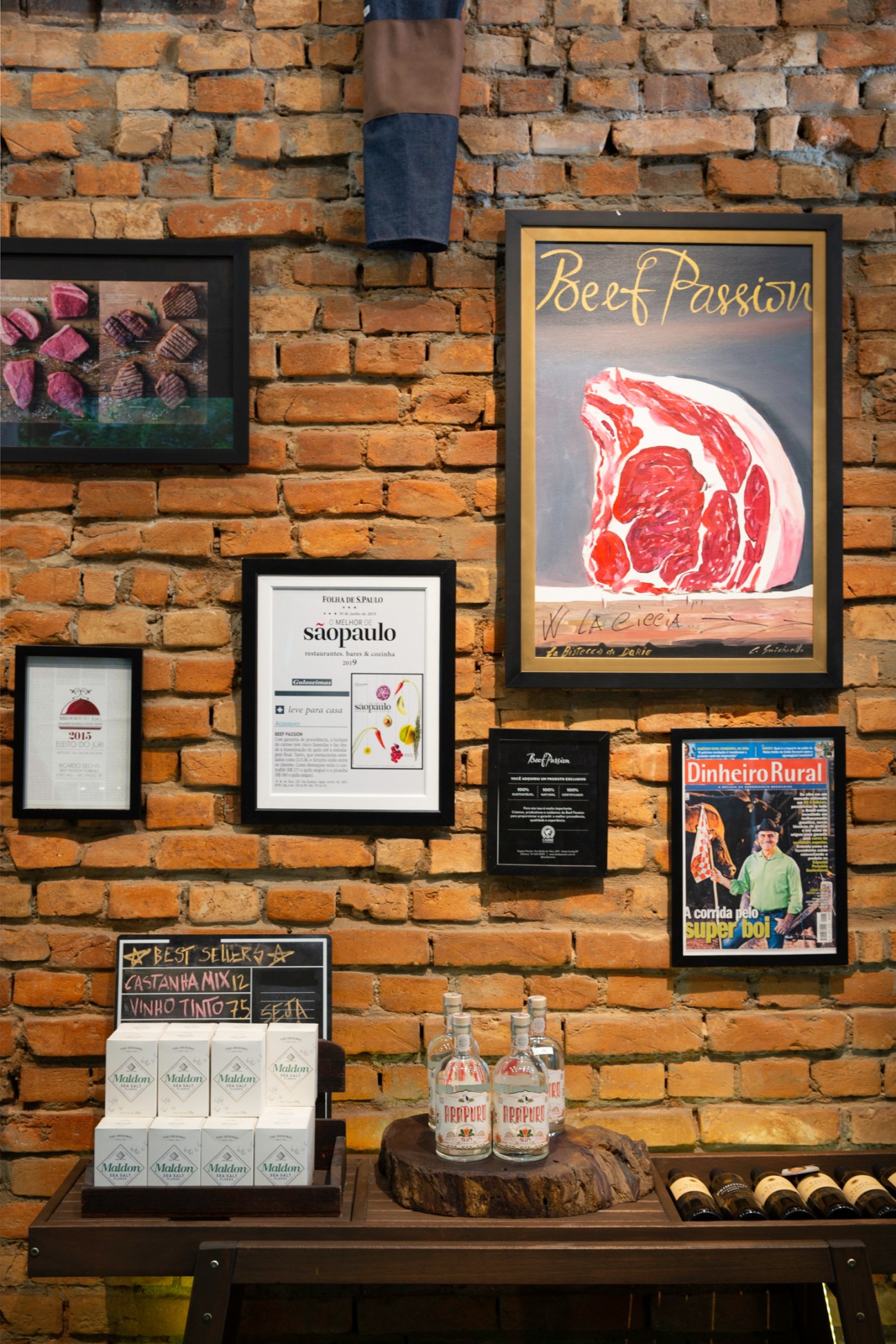 Interior wall of Beef Passion butcher shop displaying framed certificates, beef illustration poster, and bottled products