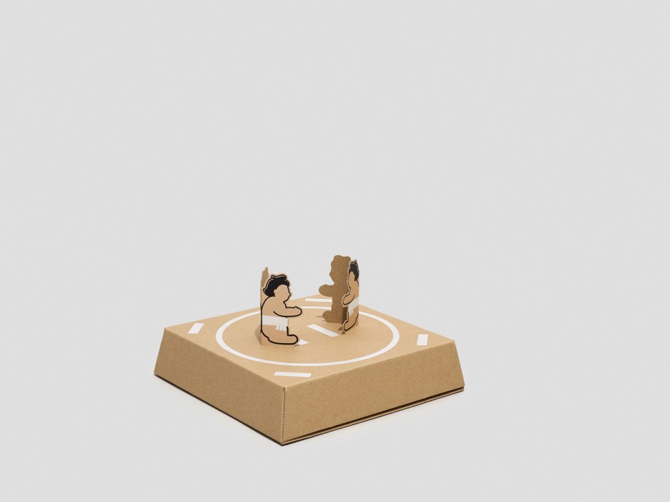 Cardboard box assembled as kami-sumo Japanese wrestling toy figures on circular arena base.