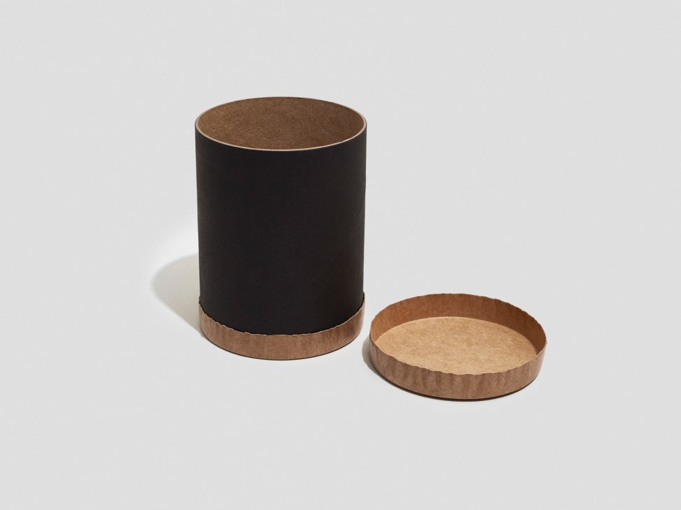 Black cylindrical canister with brown corrugated base and lid made from recycled paper.