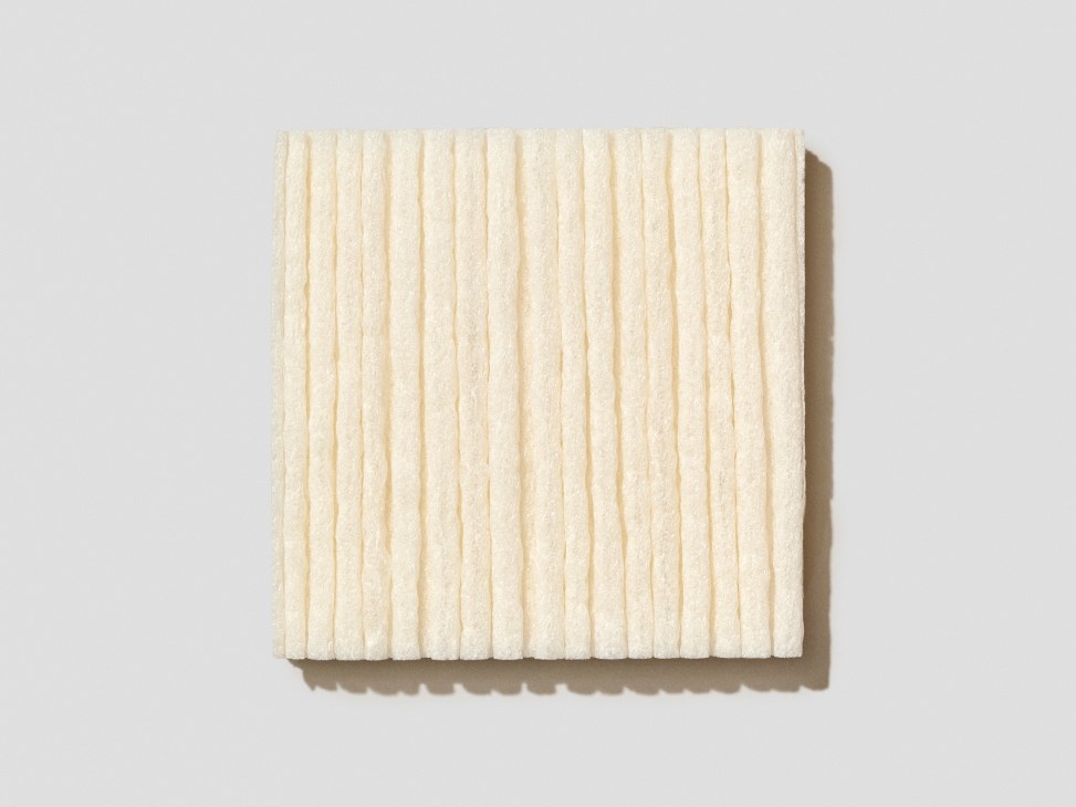 Square sample of cream-colored water-soluble cornstarch foam with vertical ribbed texture.