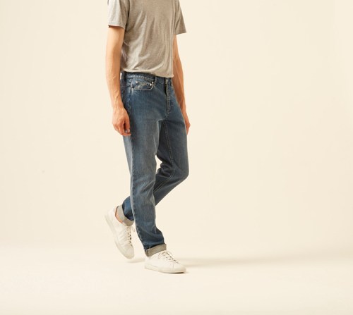 Man wearing dark blue baggy jeans by APC with a gray t-shirt and white sneakers.