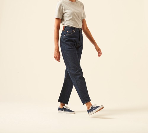 Woman wearing Monroe jeans by Chimala in raw selvedge denim with vintage-inspired fit and beige t-shirt.