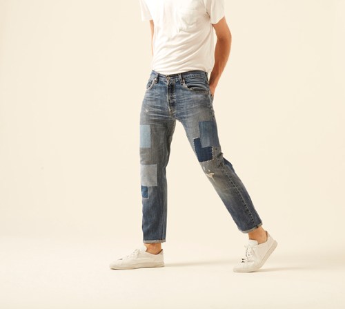 The Detroit jeans by Atelier & Repairs worn with white sneakers and white t-shirt, showing heritage-style patchwork construction in deep indigo denim.