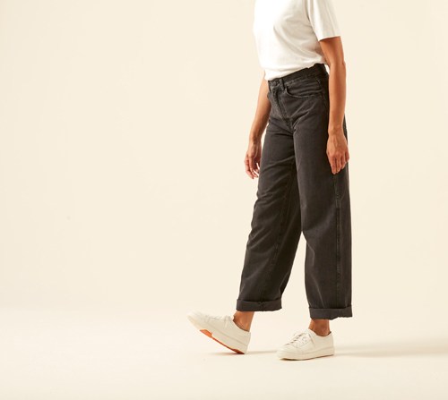 Model wearing high-rise straight leg jeans by Uniqlo in classic blue wash with white sneakers