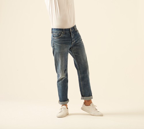 Model wearing Social sculpture dry denim-6 by Visvim with white top and cream sneakers.