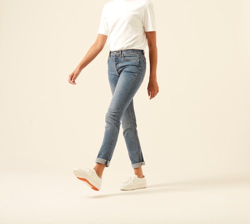 Woman wearing APC Petit new standard jeans in slim fit dark indigo with white t-shirt and white sneakers.