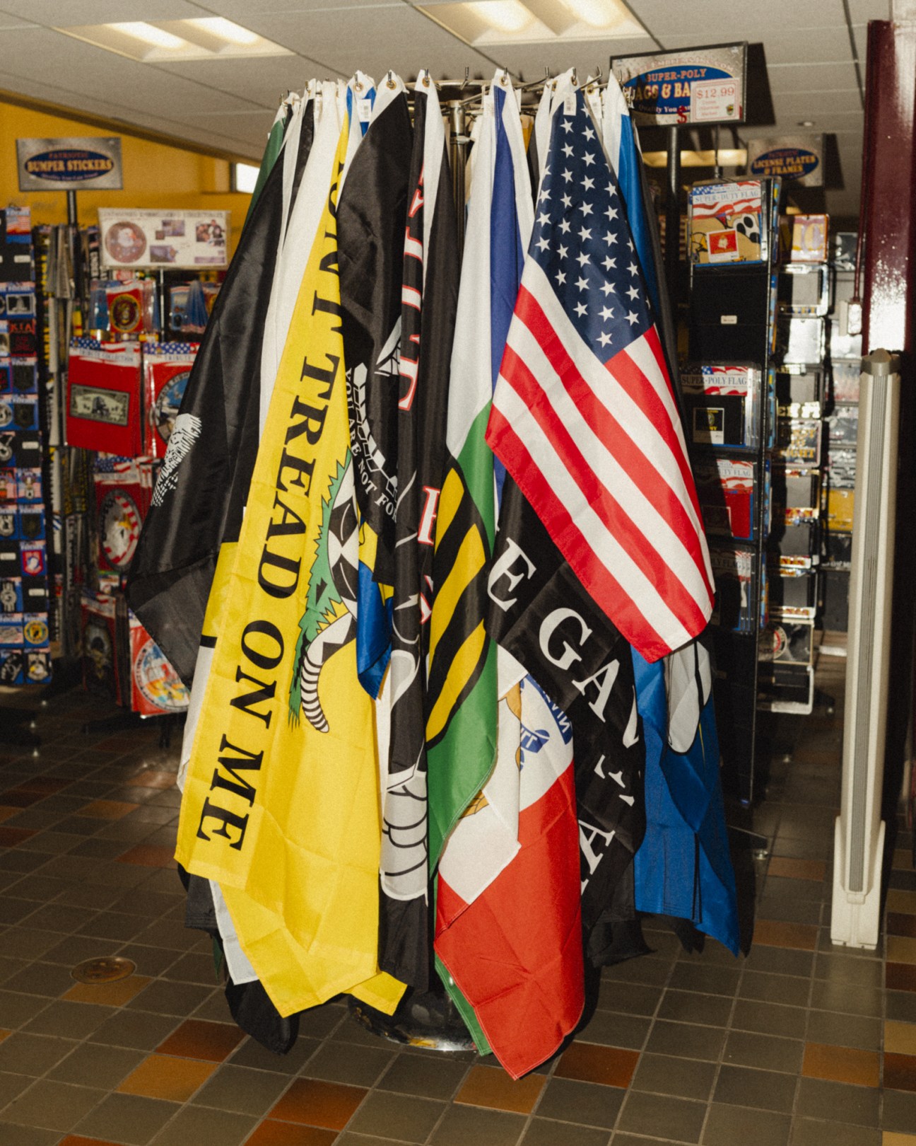 Various flags hanging on display at a truckstop, including the American flag and trucker-themed flags.