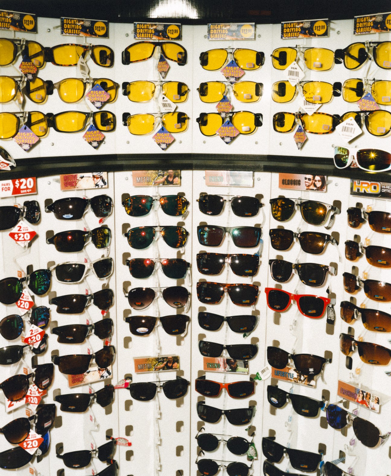 Display wall of sunglasses in various styles and colors with price tags at a truckstop.