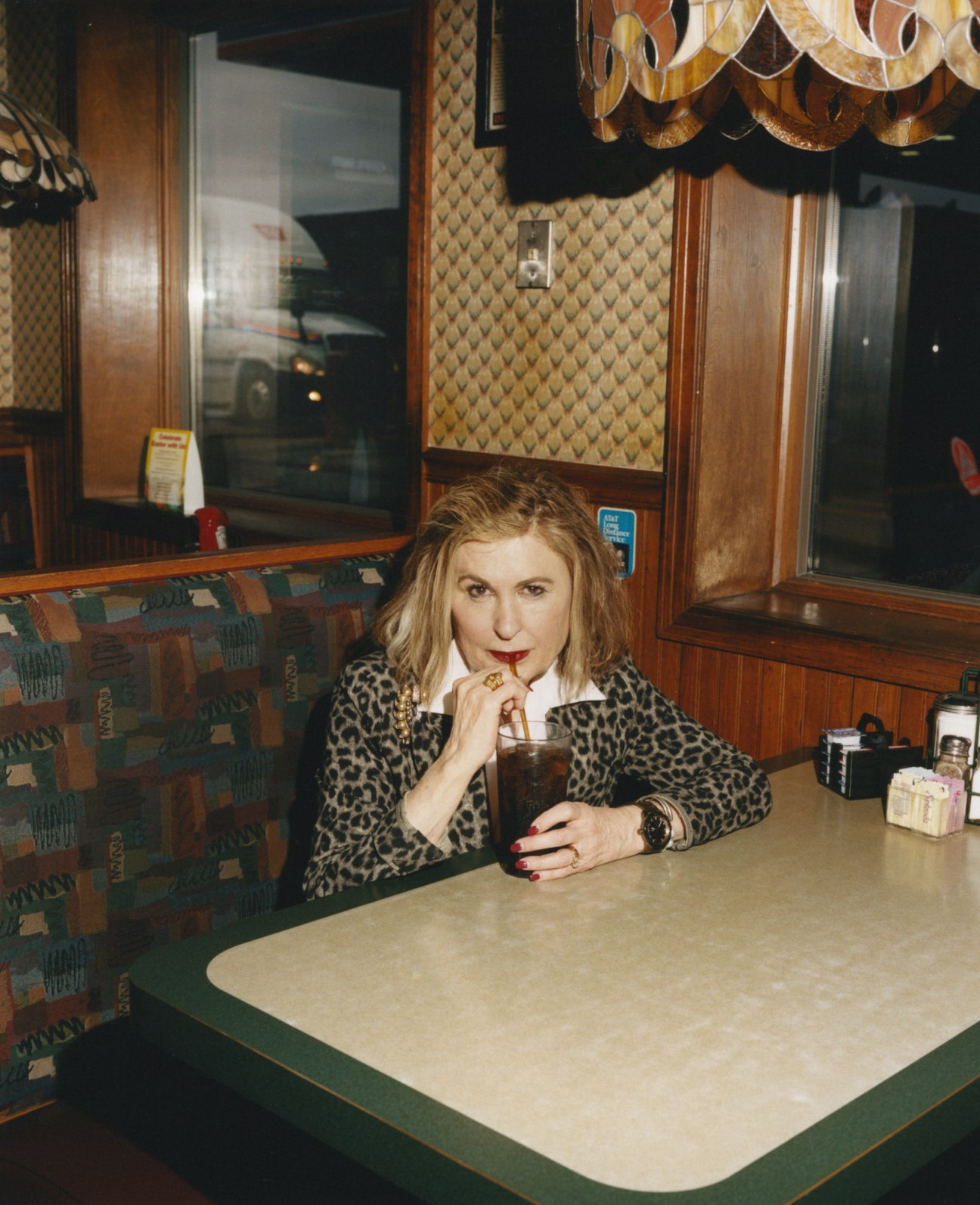 Kathie Romines, 71-year-old manager of R Place restaurant, sitting in a booth with a drink.