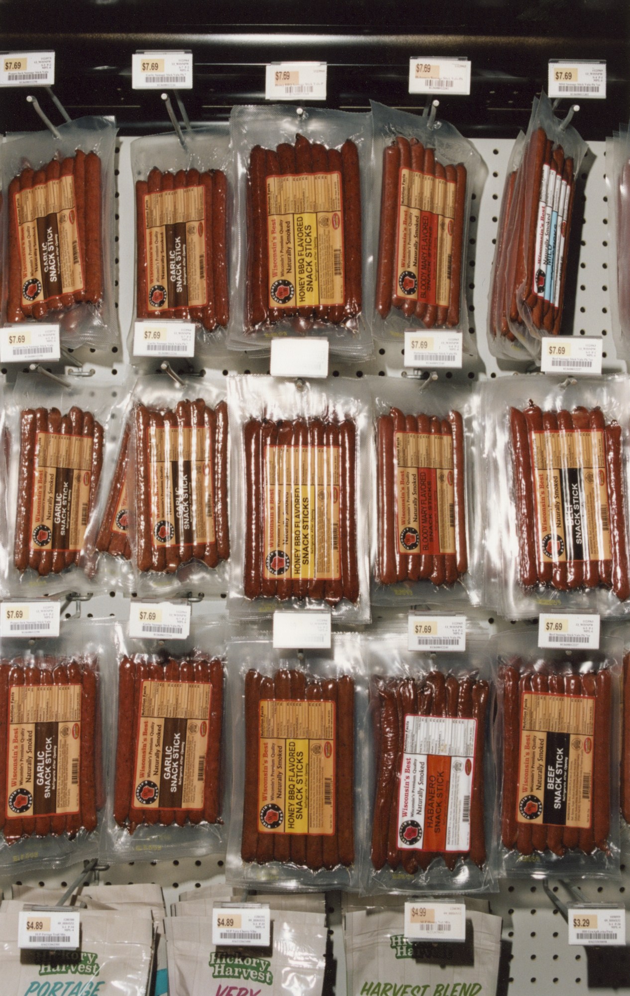 Packaged smoked meat and sausages displayed on retail shelves with price tags at a truckstop.