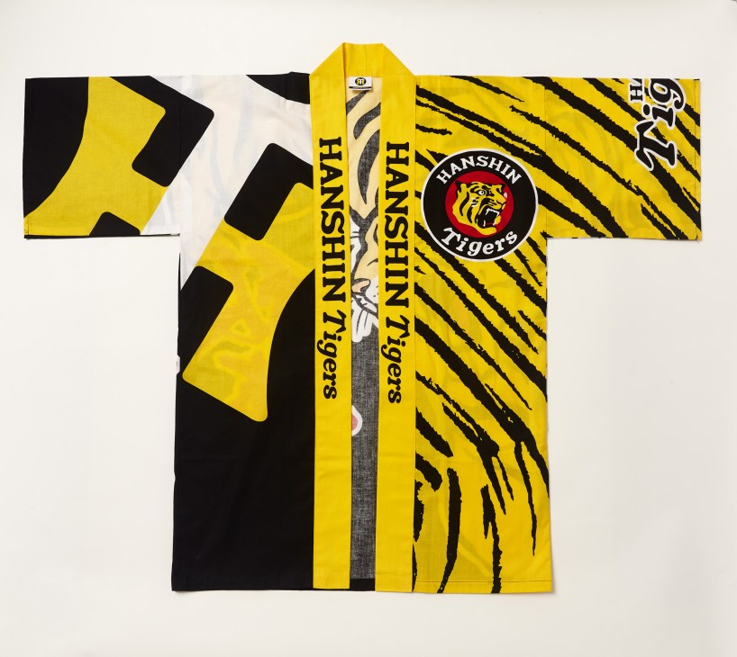 Hanshin Tigers yellow and black striped baseball uniform laid flat displaying team logo and traditional Japanese design details.