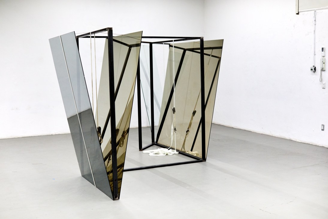 Contemporary sculptural installation with angular mirrored panels and black metal framework in white gallery space