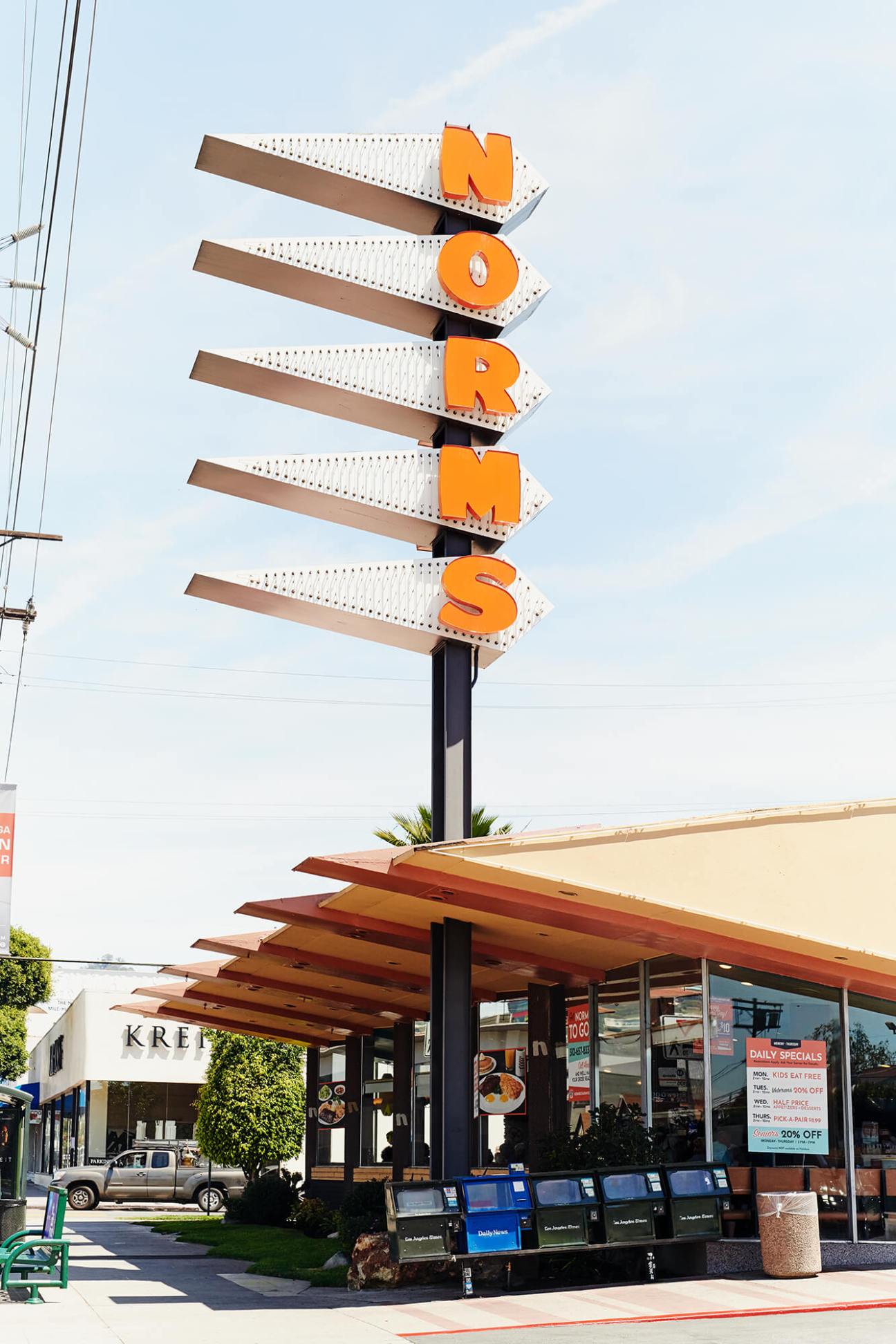 Norms diner exterior with distinctive orange vertical signage and angular mid-century modern architecture