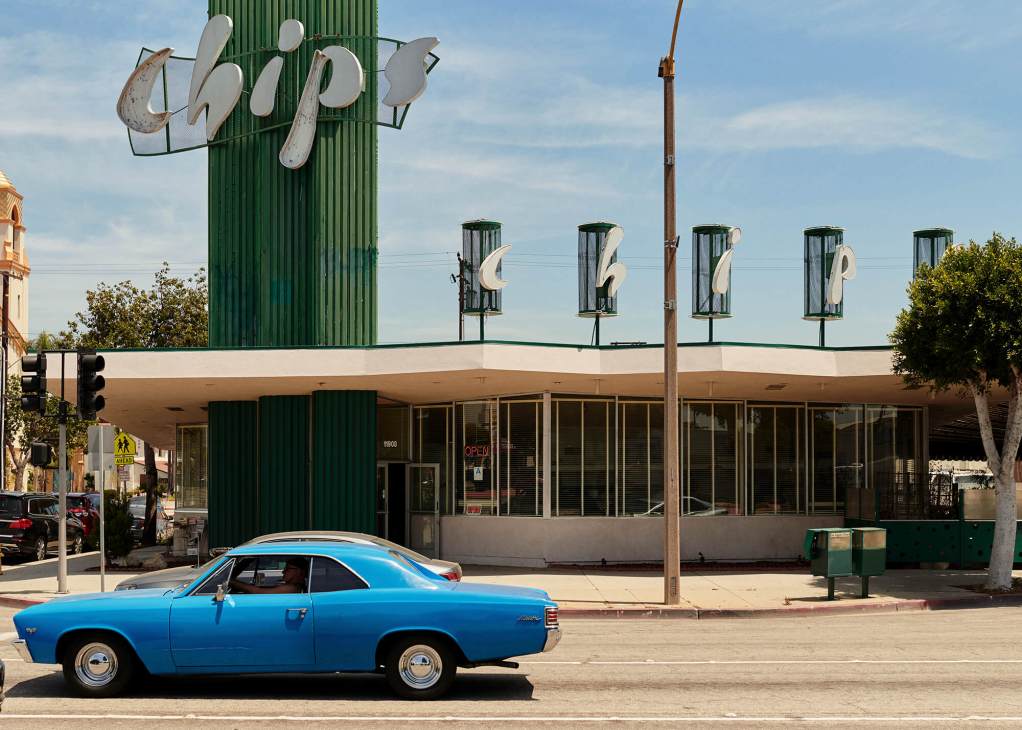 Chips diner exterior with vintage signage on green cylindrical tower and blue classic car parked outside.