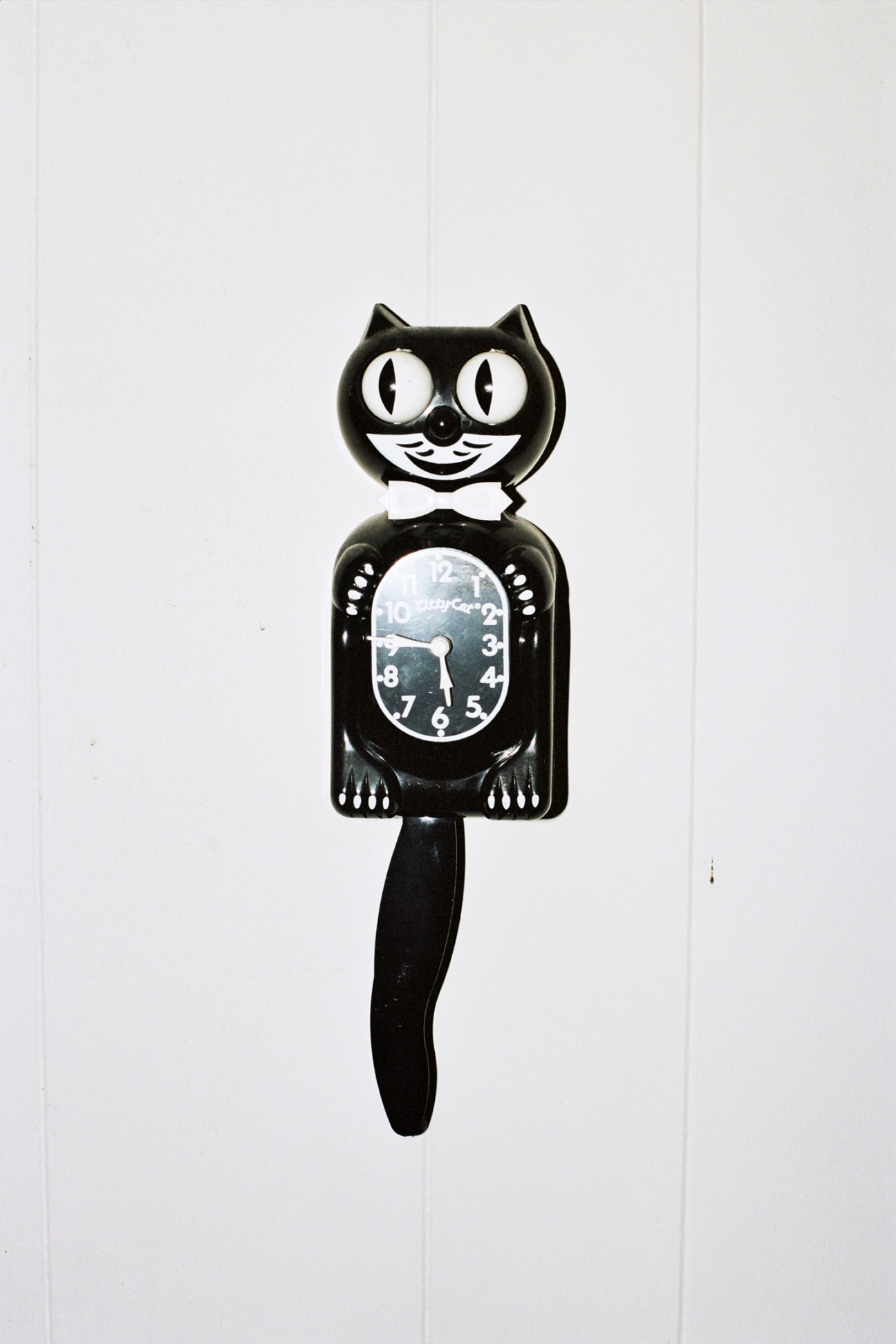 Black cat-shaped wall clock with white eyes and pendulum tail