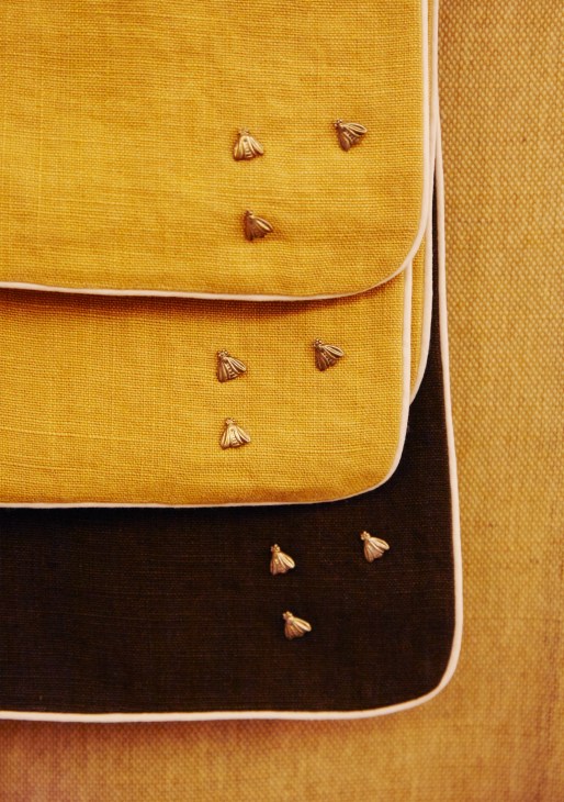 Yellow and black cushions with decorative brass shell buttons displayed at Maison Rucher.