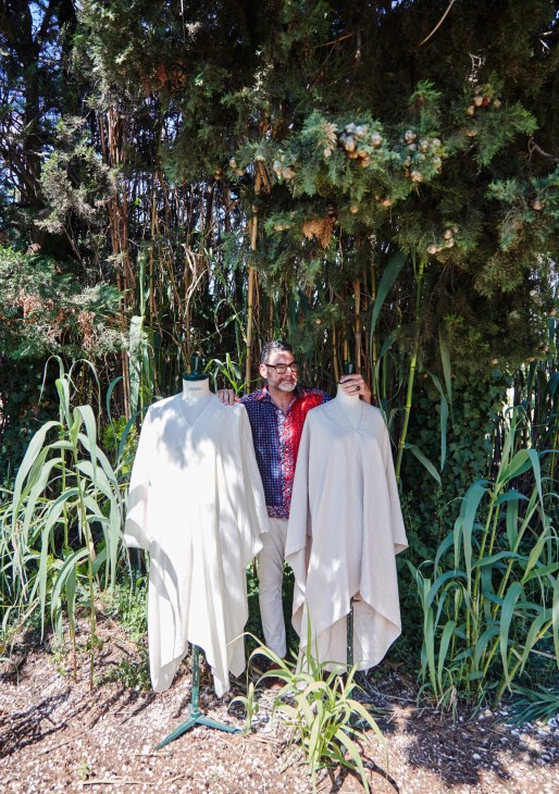 Fashion designer Eric Bergère displays two cream-colored bochi dresses on mannequins in his lush garden.