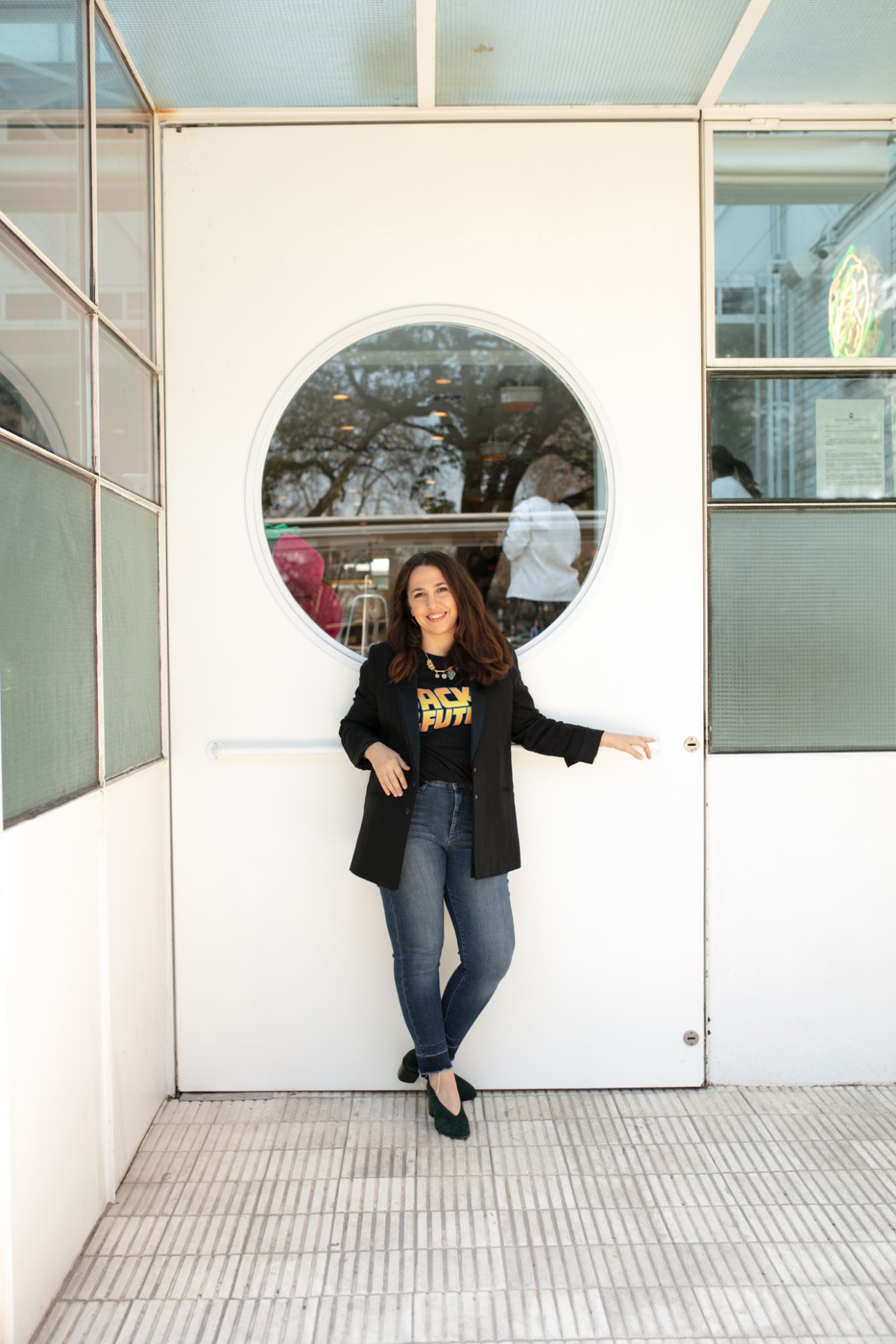 Chef Narda Lepes standing in front of Home hotel's modern circular window entrance.