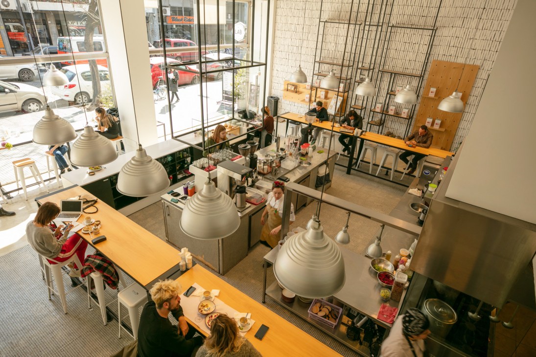Overhead view of Lab Tostadores de Café with pendant lamps, wooden counter seating, and customers dining in a bright, minimalist café space.