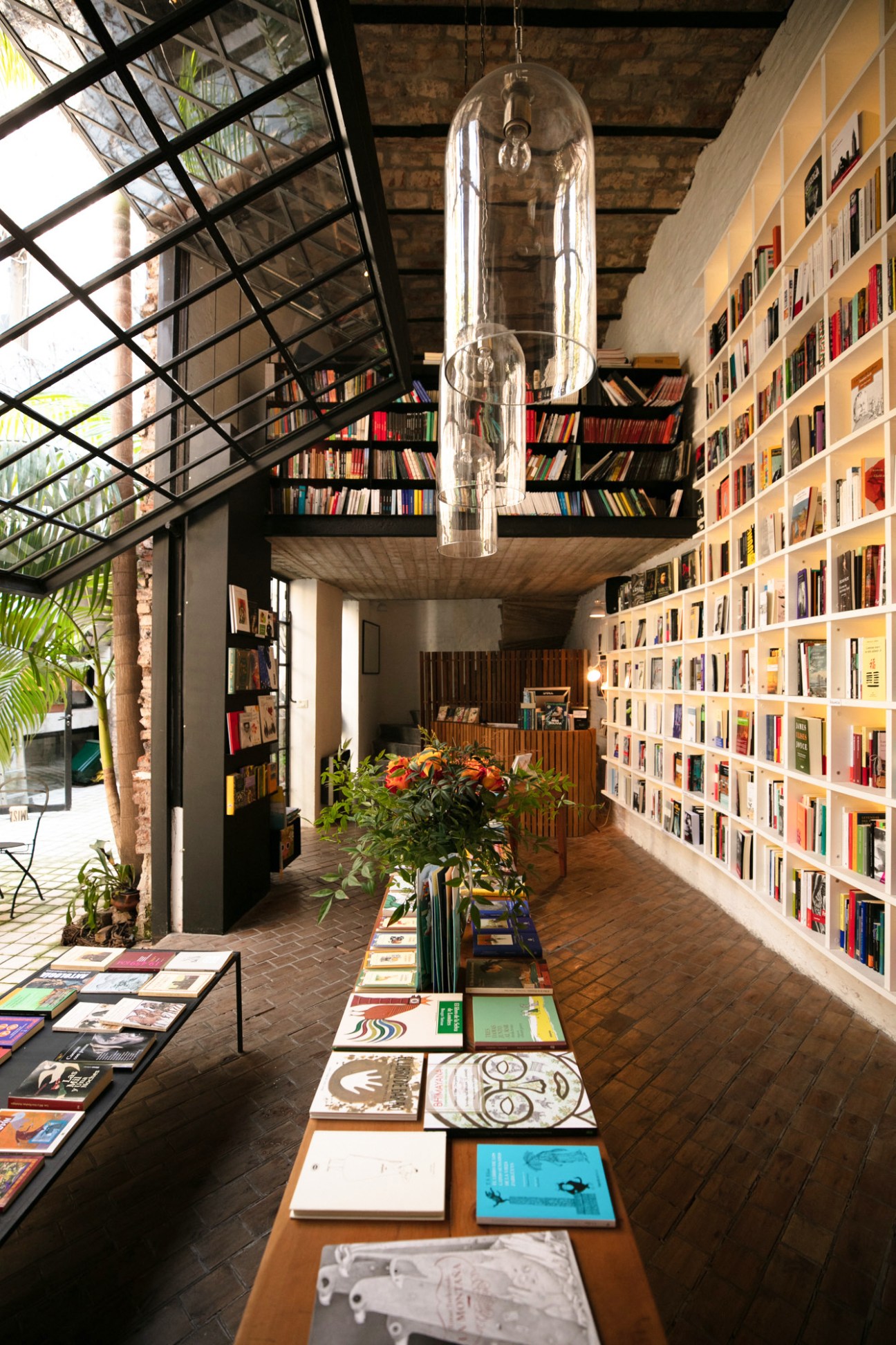 Interior view of Falena bookshop with floor-to-ceiling shelves, hanging pendant light, and displayed publications.