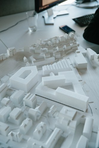 White architectural scale model of a neighborhood development with multiple small buildings arranged on a surface