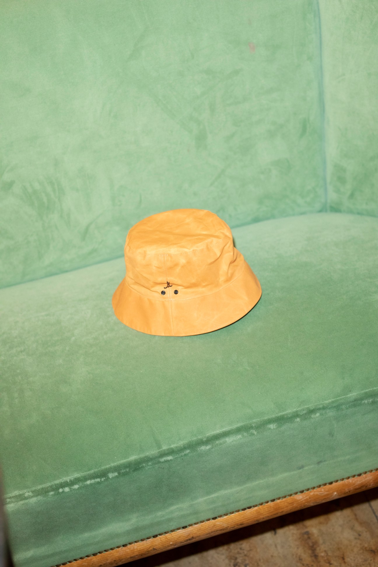 Yellow bucket hat by Mühlbauer sitting on a mint green velvet armchair