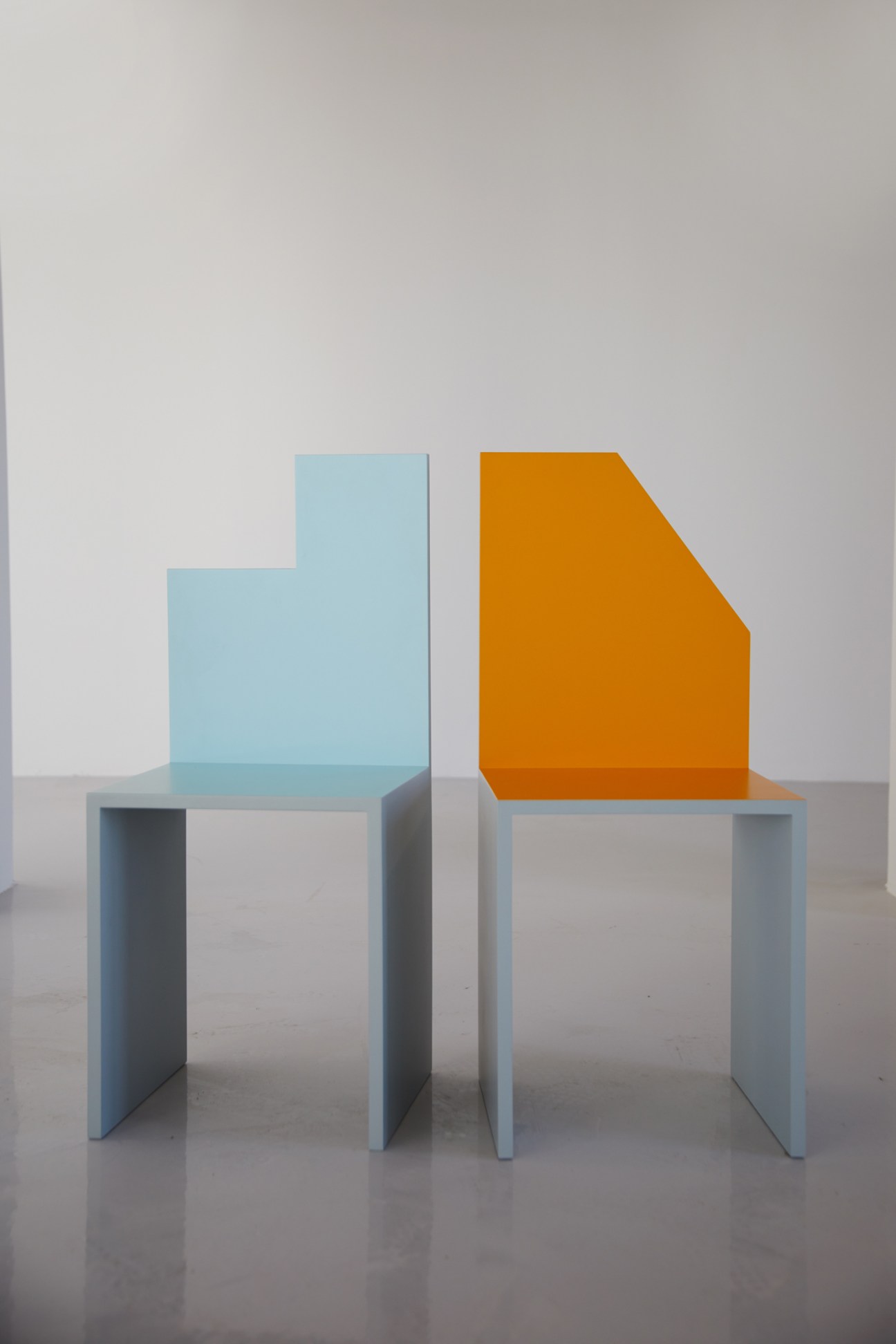 Contemporary art installation featuring blue and yellow chairs in a gallery setting