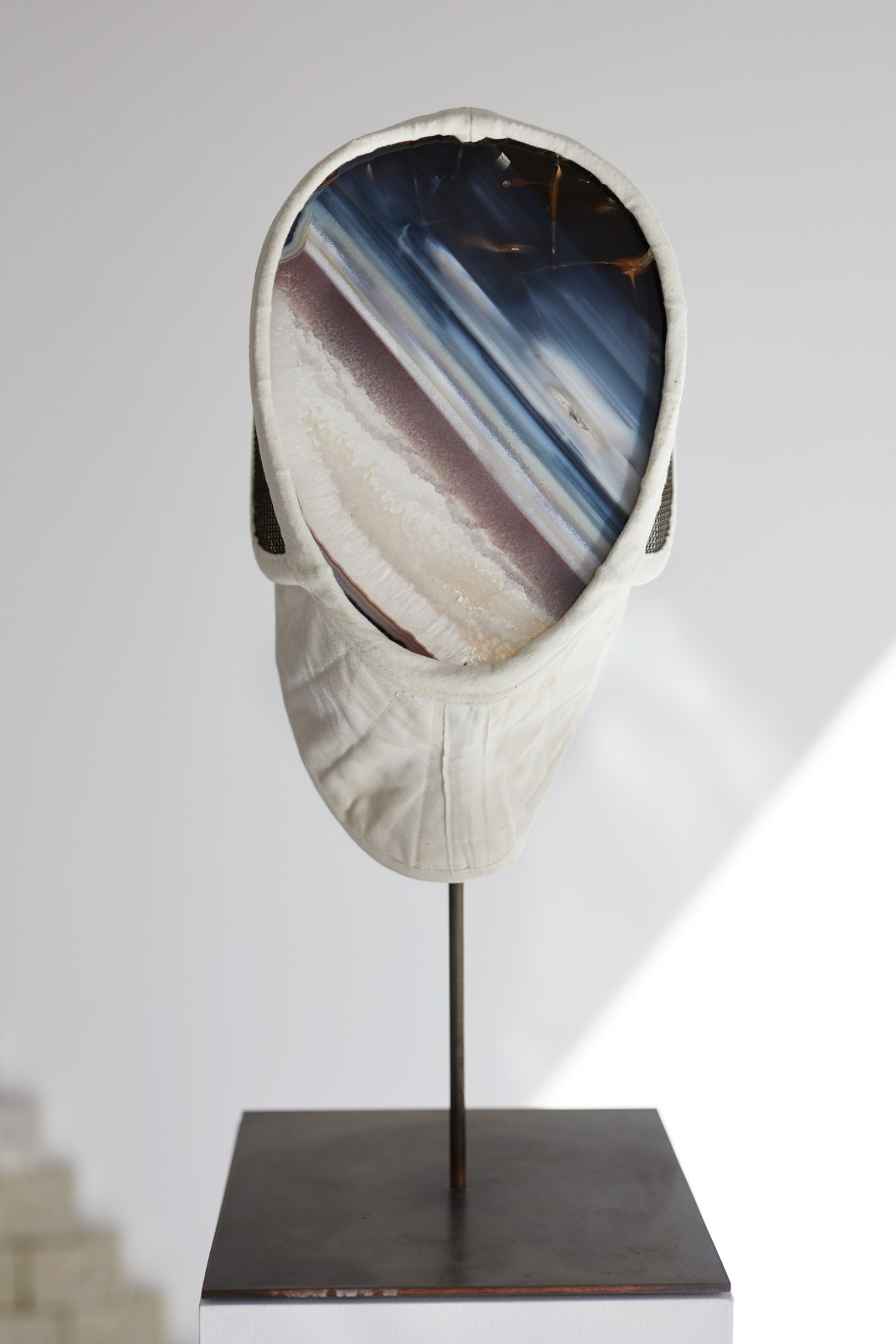 Contemporary artwork featuring a face-like sculptural form displayed in a gallery