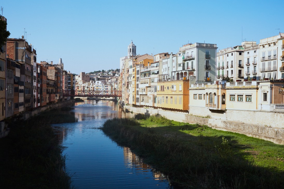 Colorful buildings line the Onyar River in Girona with a bridge connecting both sides