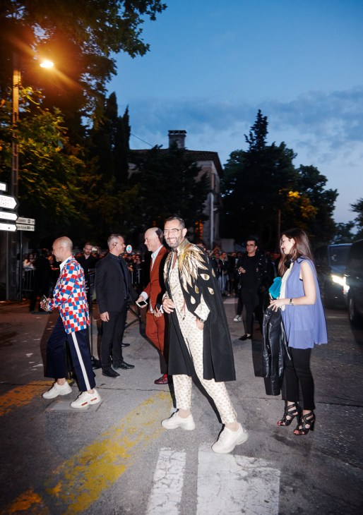 Stylishly dressed attendees gathering at a Gucci event on a twilight street in Arles.