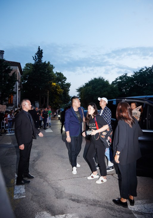 Guests and attendees arrive at Gucci's Resort show in Arles, mingling on a street lined with spectators.