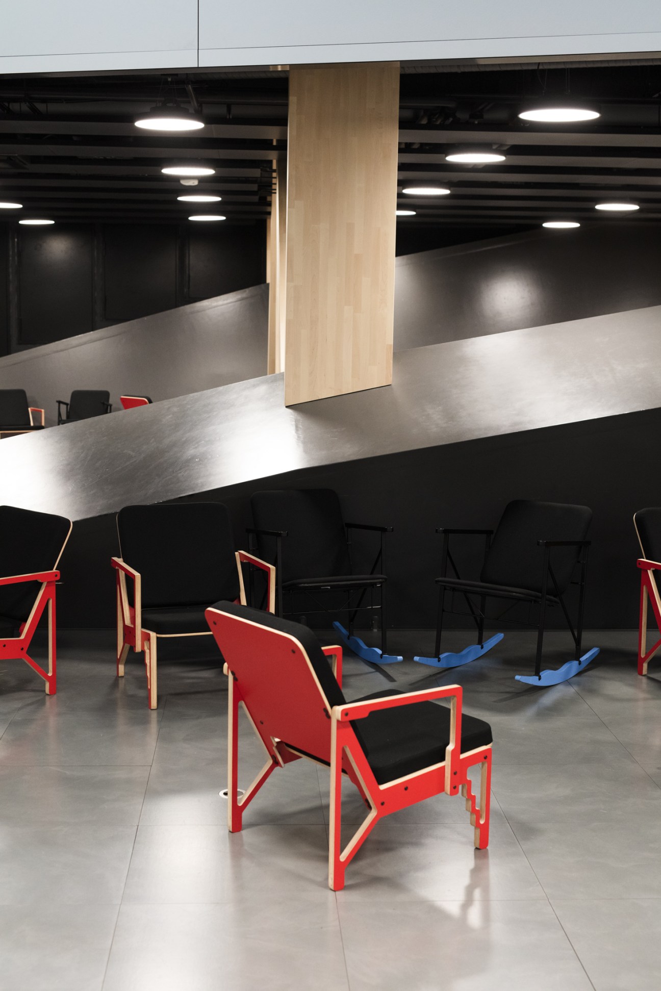 Yrjö Kukkapuro's CNC-1 chairs in red and black displayed in a modern interior space with wooden column and ambient lighting.