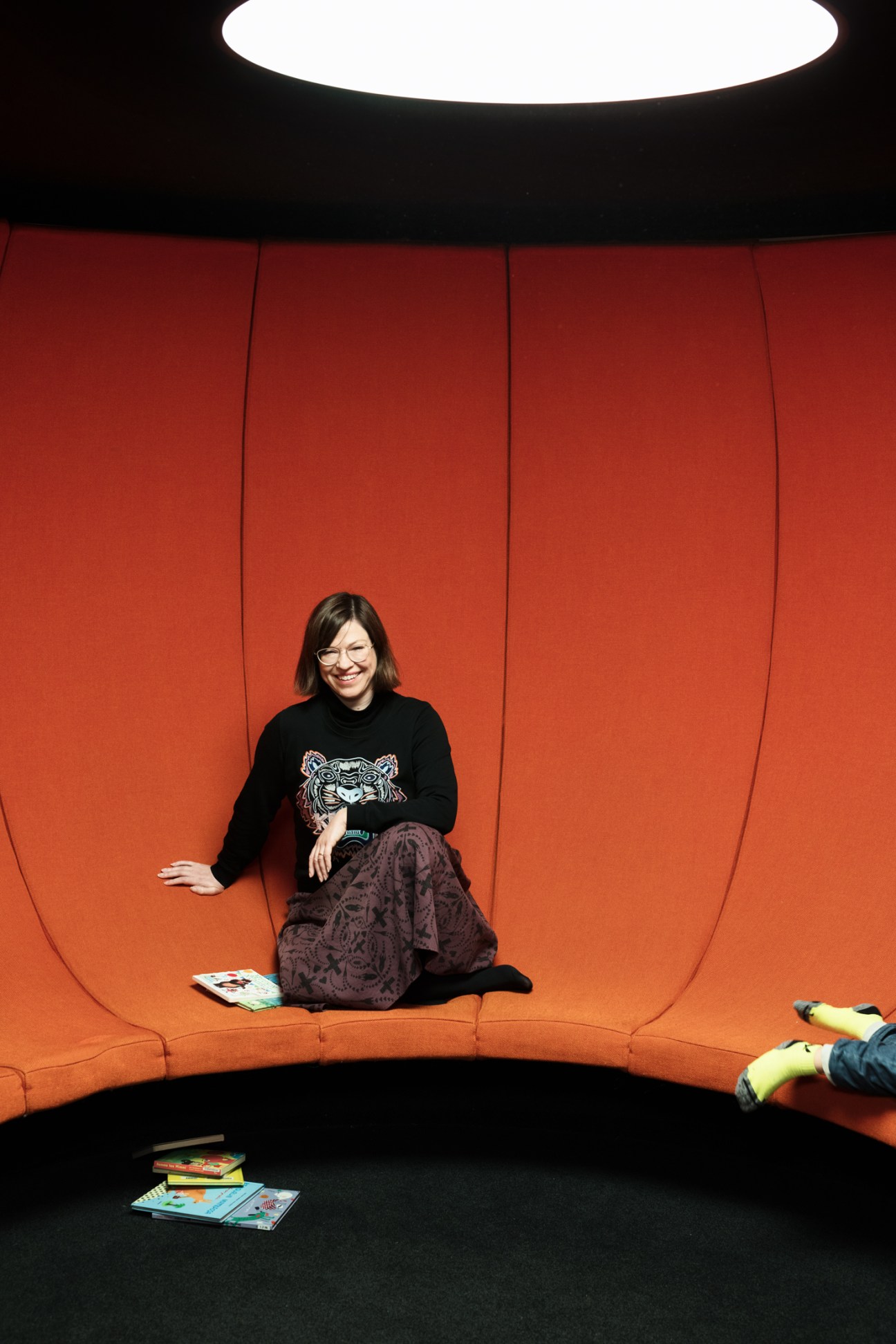 Deputy mayor Anni Sinnemäki sitting in a padded orange alcove at Oodi Library.