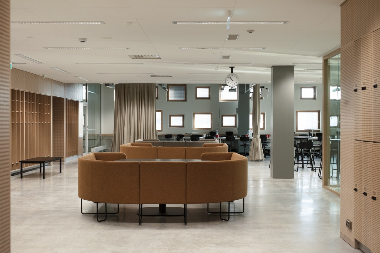 Modern classroom with curved tan seating, brick walls, and large windows at Jätkäsaari School in Helsinki.