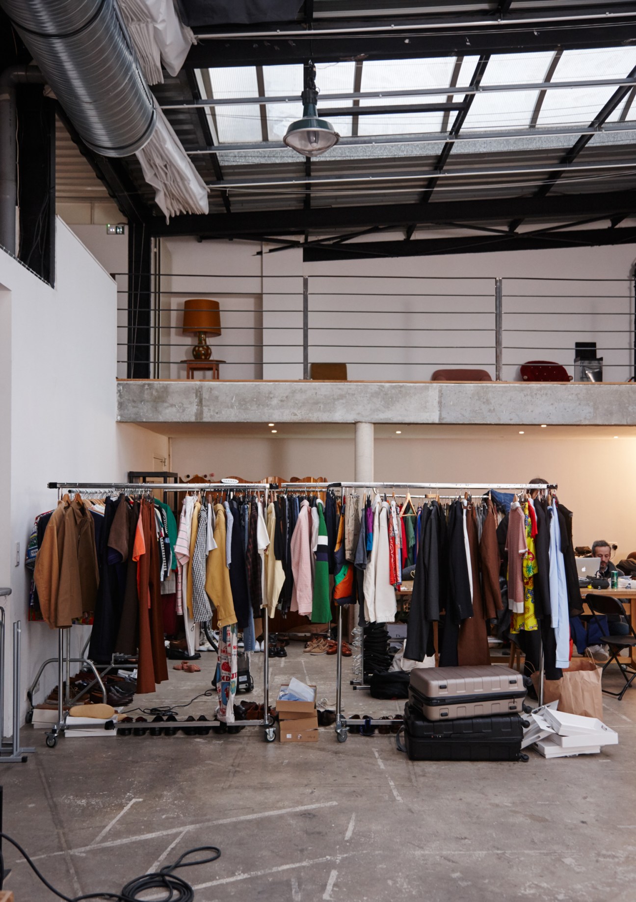 Clothing racks with various garments and accessories arranged in an industrial studio space.